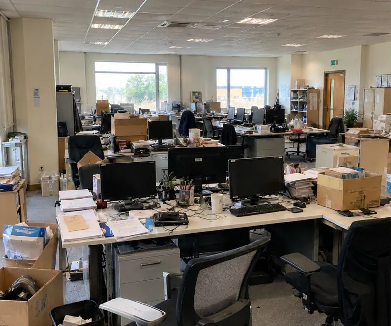 Kantoorverdieping vol bureaus, stoelen, beeldschermen en dozen